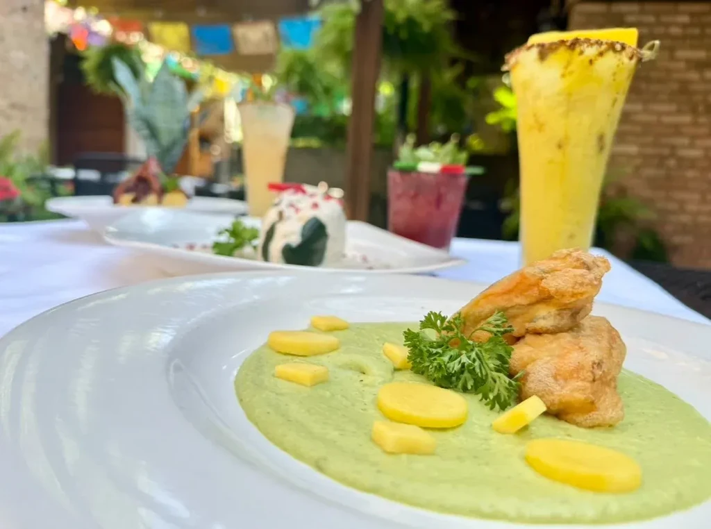 Plated fried food, green purée, yellow garnish in a restaurant.