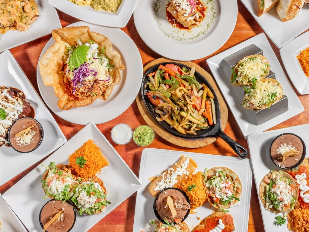 Top-down view of a rustic table laden with Mexican dishes.