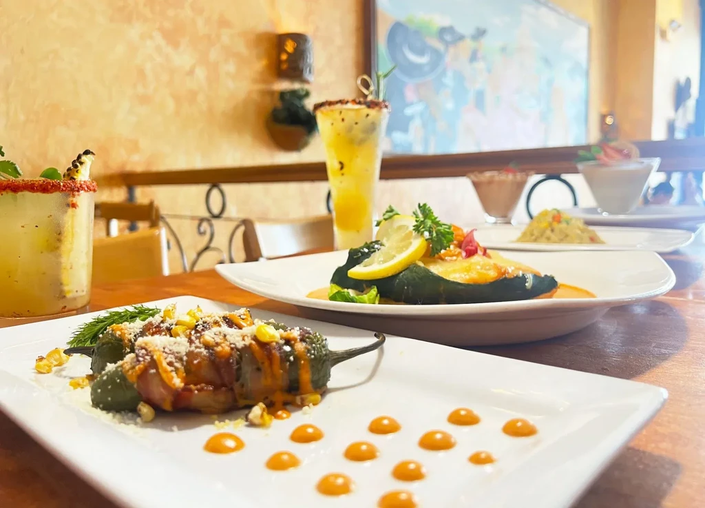 Plates of stuffed peppers, drinks, and other food on a table.