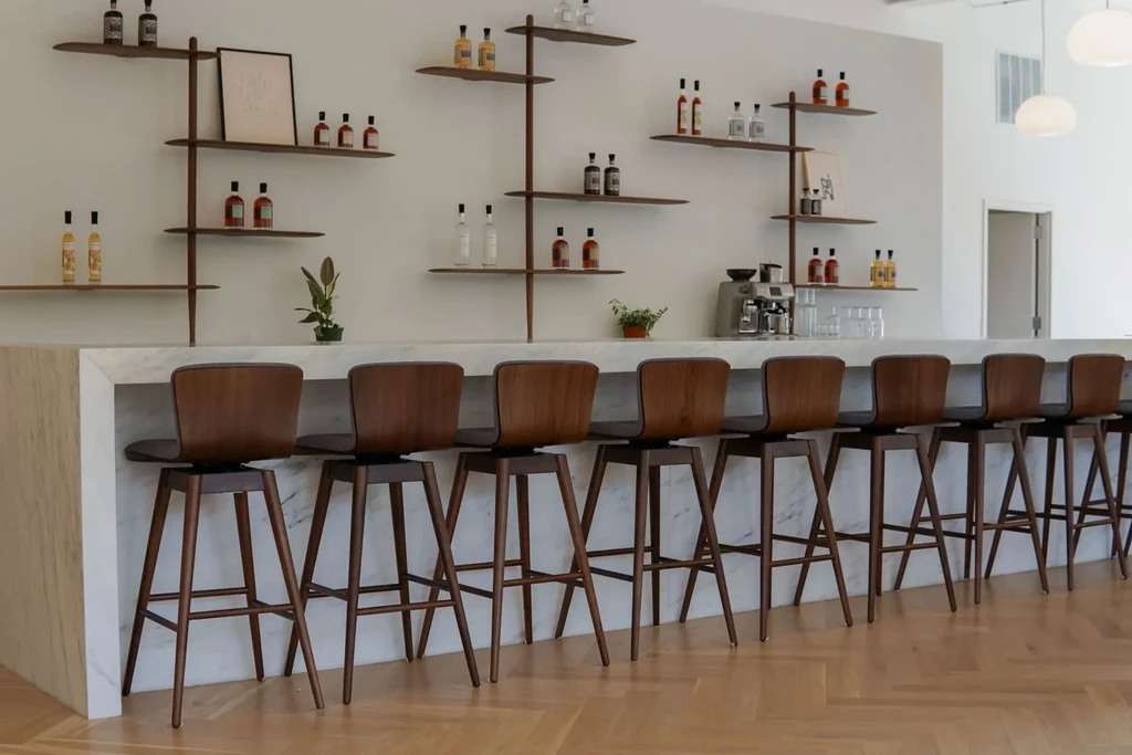 Modern bar interior with a marble counter and wooden bar stools.