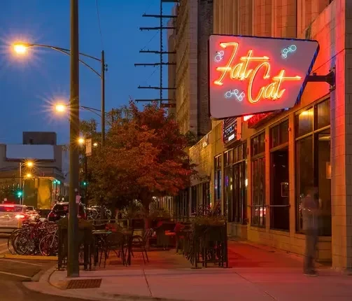 "Fat Cat" restaurant exterior at dusk with prominent orange neon sign.
