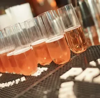Stemless flutes with pink sparkling beverage on a textured mat.