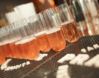 Stemless flutes filled with pink, foamy, sparkling beverages on a bar mat.