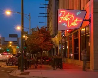 Exterior building at dusk with a neon "Fat Cat" sign.