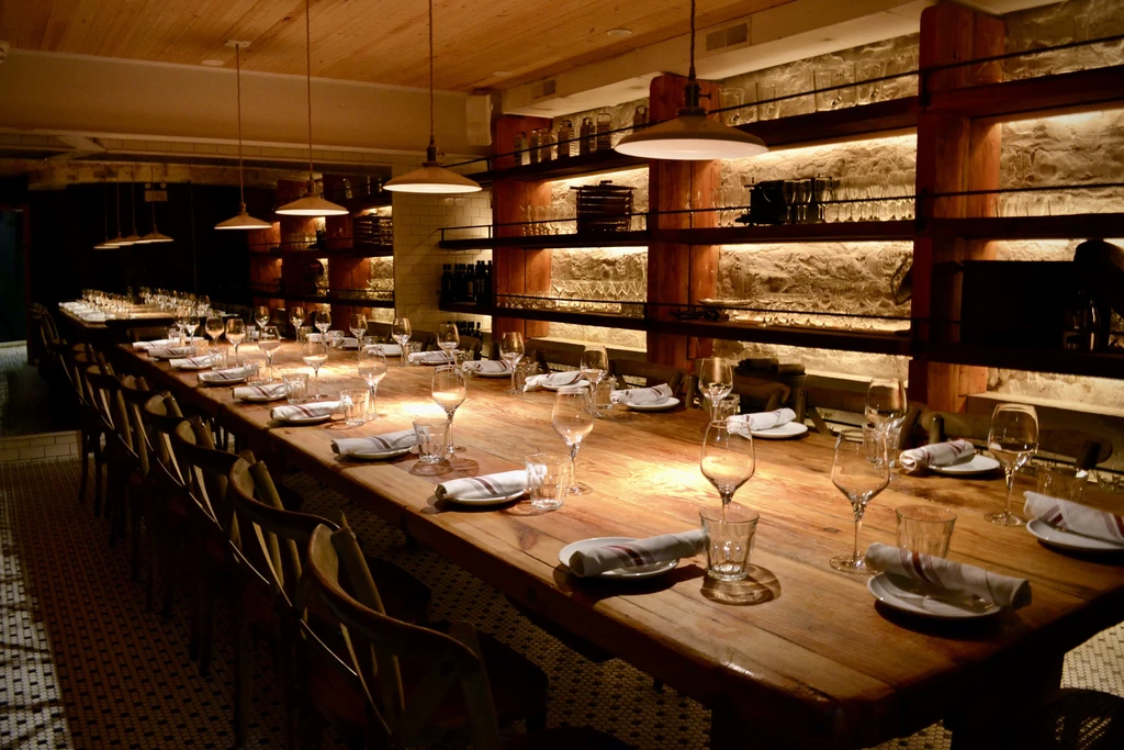 Long communal dining table in an upscale restaurant with warm lighting.