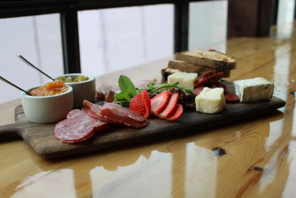 Charcuterie board with meats, cheeses, fruit, and olives.