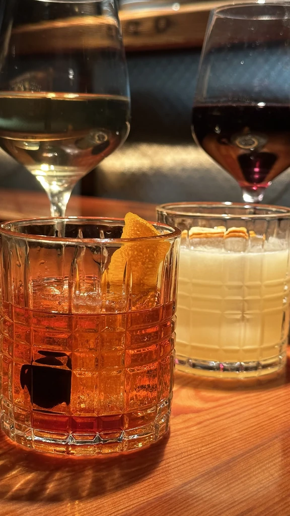 Four drinks in assorted glasses on a wooden table.