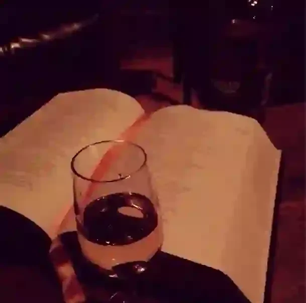 Drink glass and open menu on a dimly lit table.