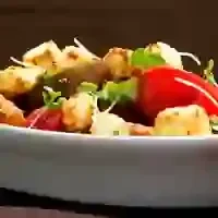 Close-up of a blurry dish with fried chunks and green vegetables.
