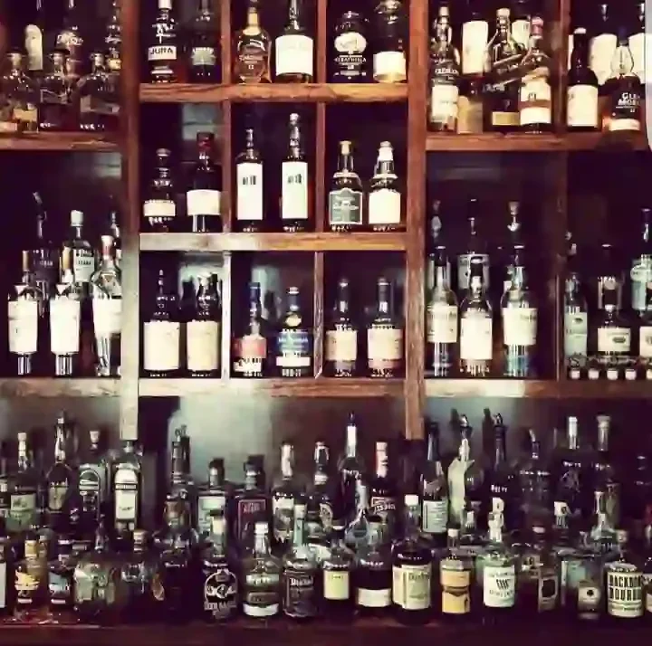 Well-stocked bar with numerous bottles of liquor on wooden shelves.