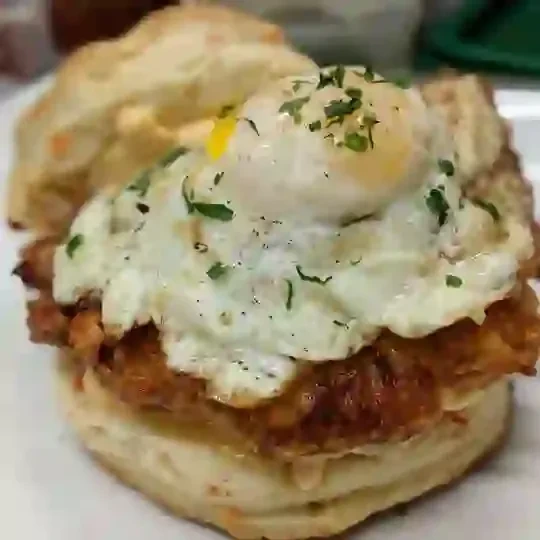 Close-up of a fried chicken, egg, and biscuit sandwich.