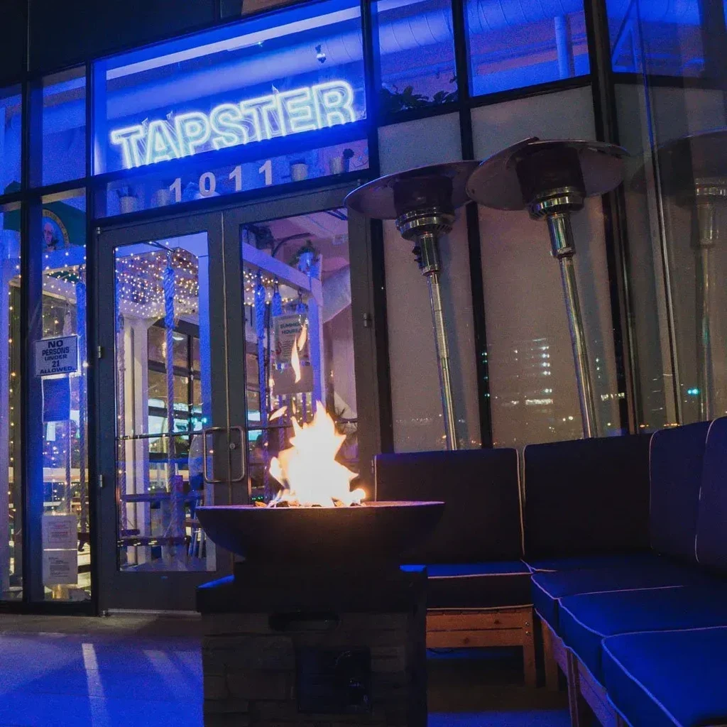 Exterior of Tapster restaurant at night with a fire pit.