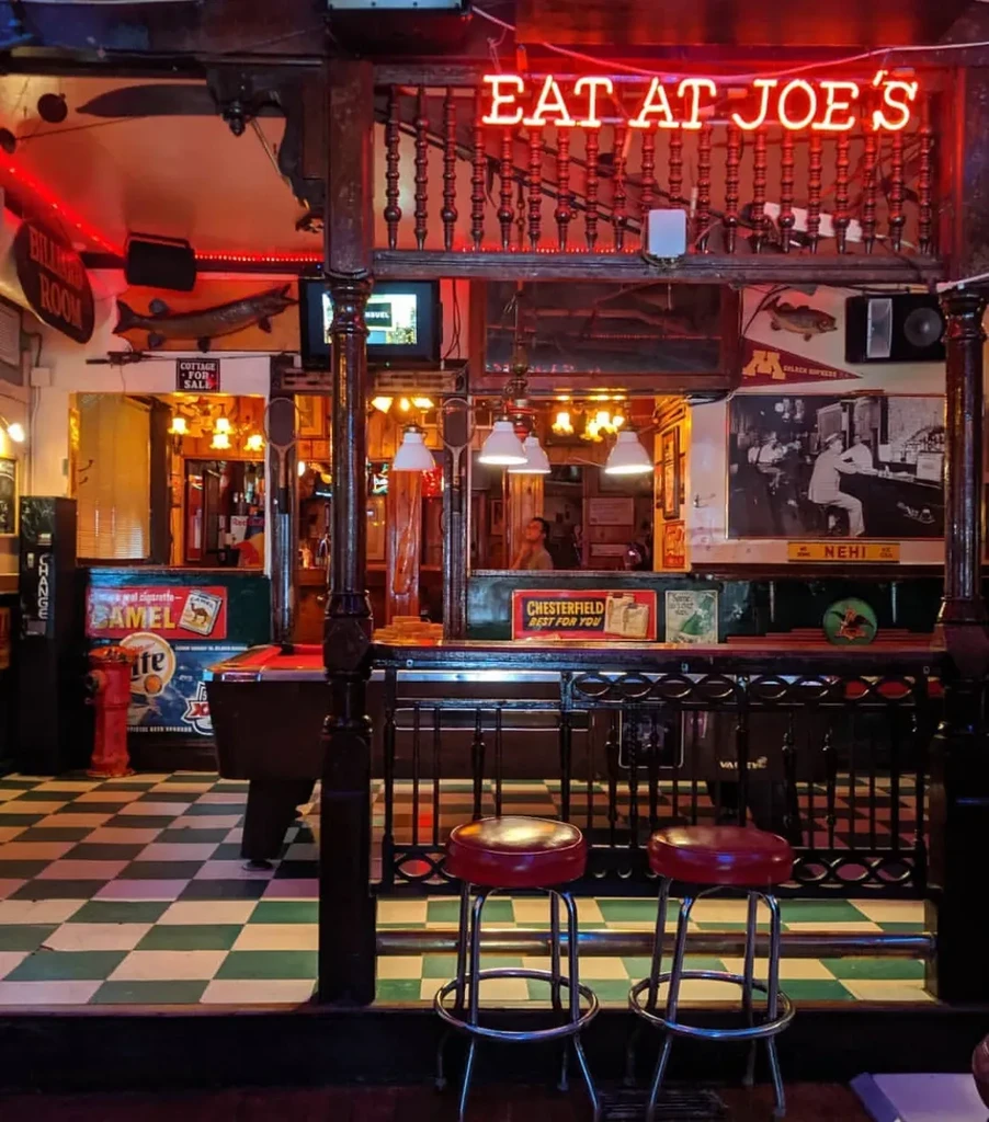 Interior of a rustic bar with a pool table and neon signs.