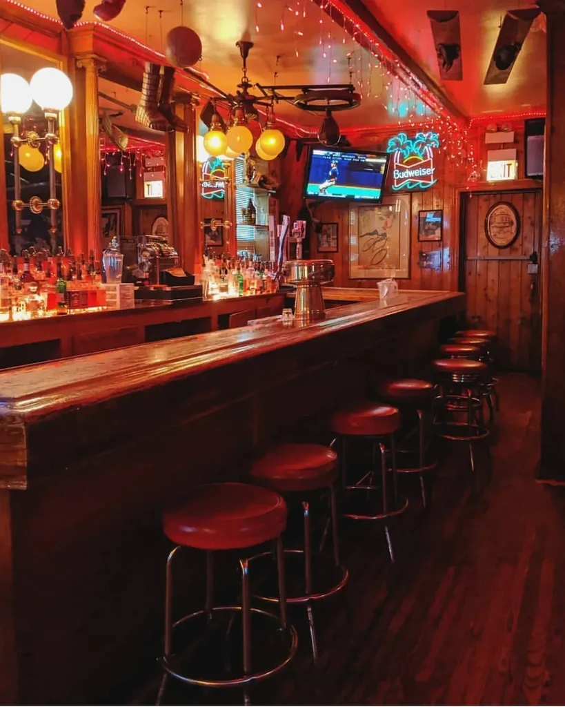 Interior of a warmly lit bar with a long wooden counter.