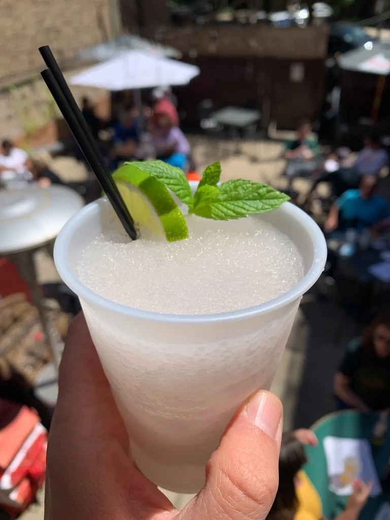 Hand holds a white cup with a garnished frozen drink.