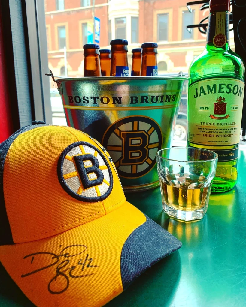 Boston Bruins cap, ice bucket, beer, and whiskey on a table.