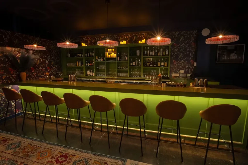 Empty bar with lime green counter and patterned wallpaper.