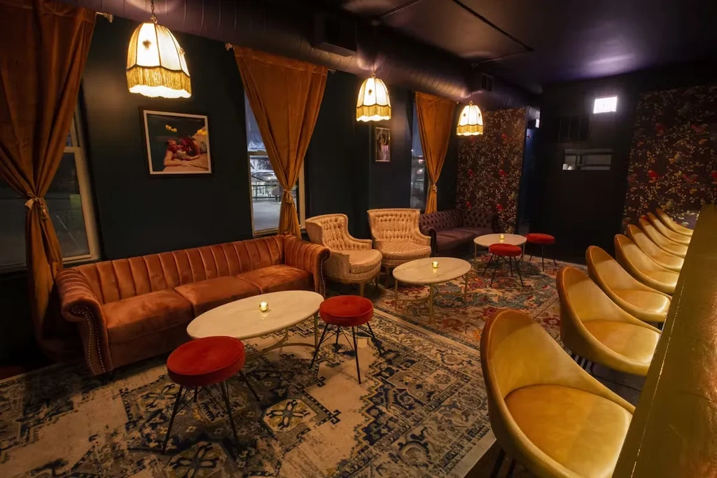 A richly decorated bar or lounge with velvet sofas and ornate rugs.
