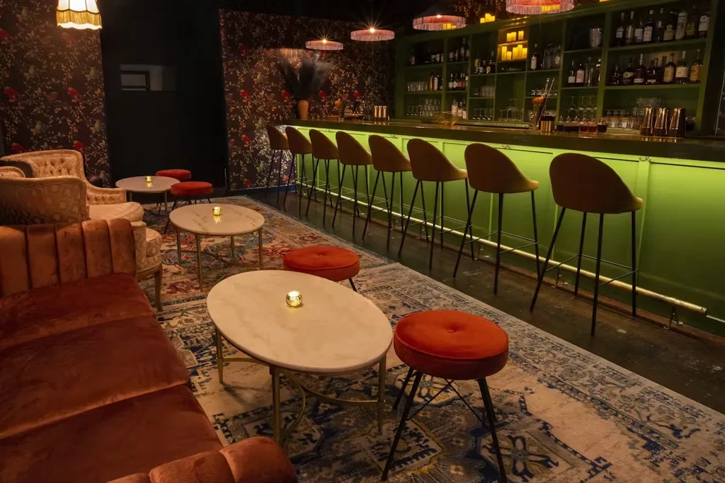 Interior of a bar with a green counter and velvet seating.