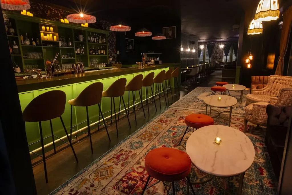 Dimly lit upscale bar with a green counter and mustard-yellow stools.