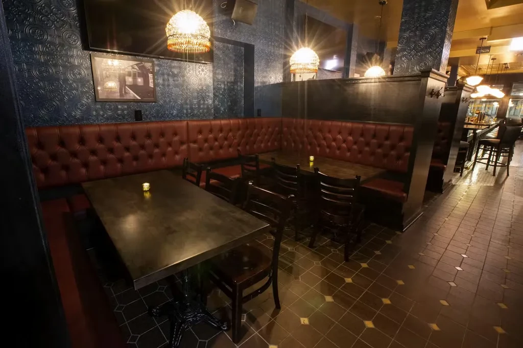 Restaurant interior with dark red booths, patterned walls, and chandeliers.