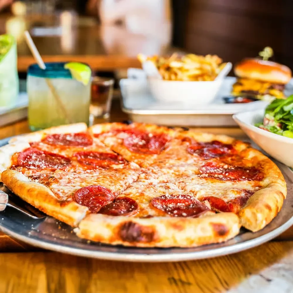 Close-up of a well-baked pepperoni pizza on a silver platter.