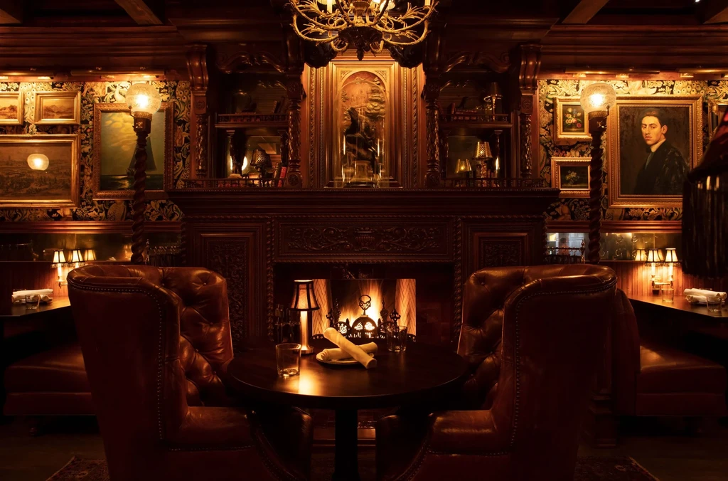 Luxurious, dimly lit room with fireplace, armchairs, and framed art.