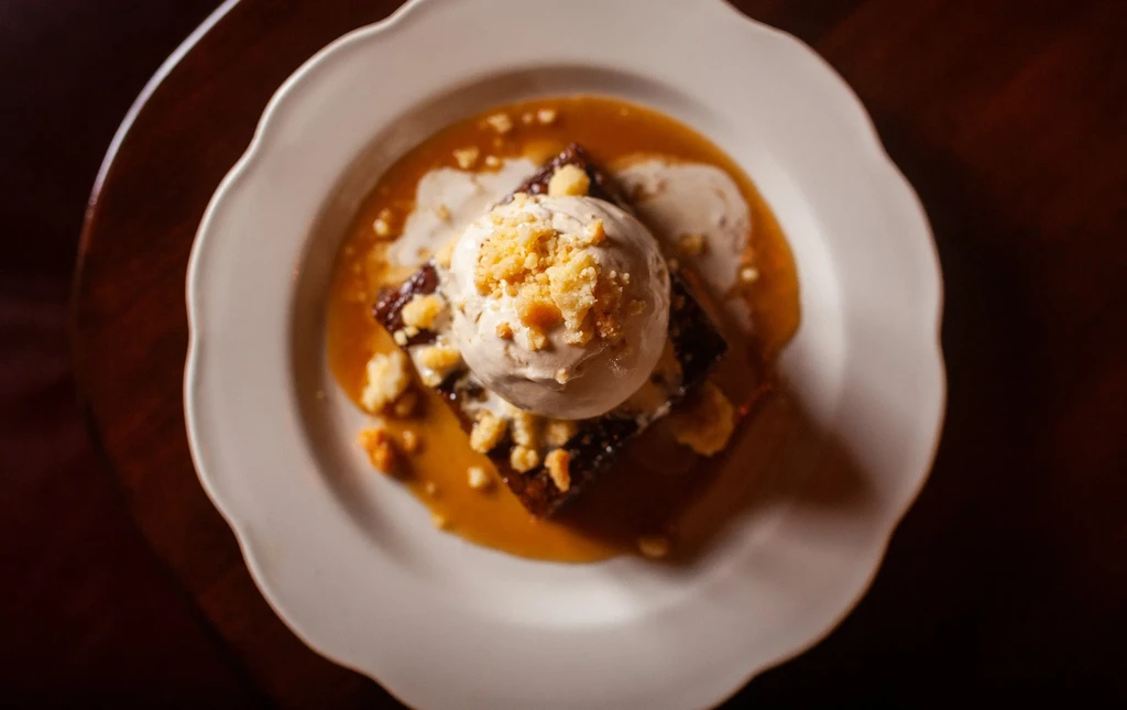 Brownie with melting ice cream, crumble, and caramel sauce.