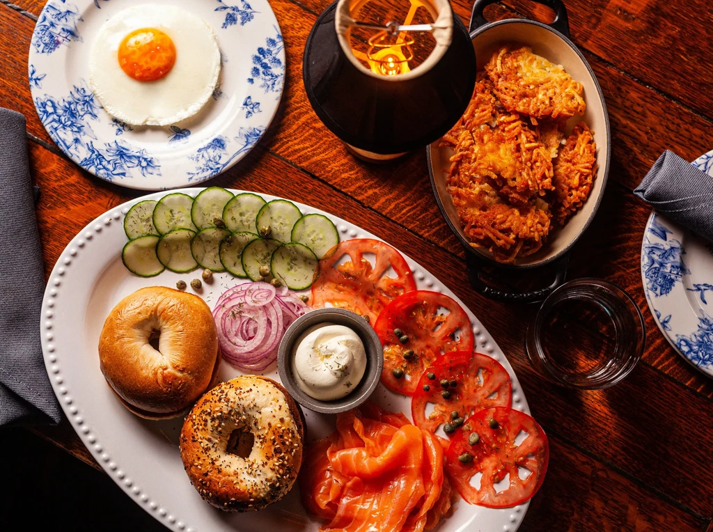 Well-arranged breakfast spread with bagels, salmon, egg, hash browns.