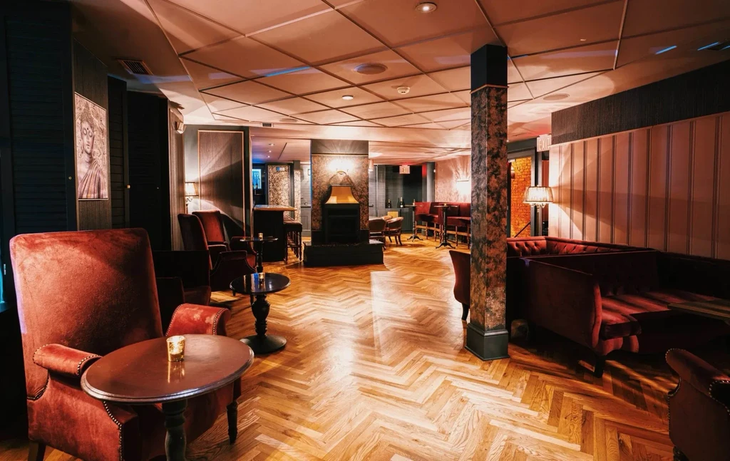 Restaurant lounge with red velvet seating, fireplace, and herringbone floor.