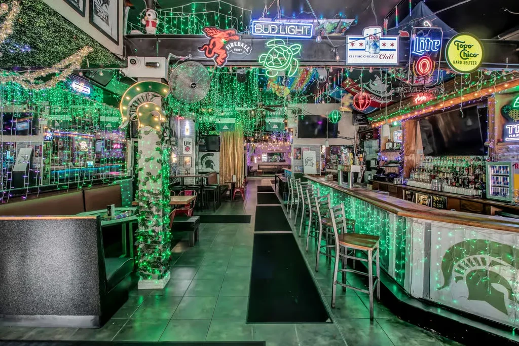Bar interior with green string lights and various neon signs.