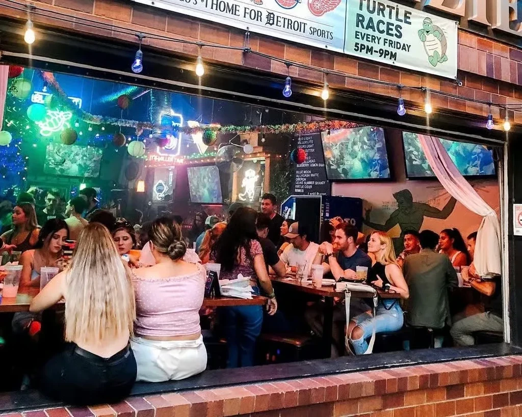 Bar interior with neon lights, TVs, and banners for sports and turtle races.