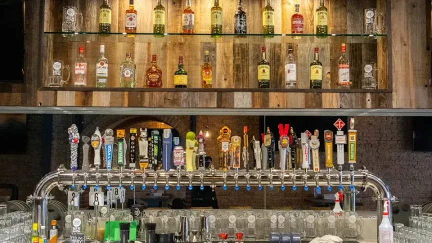Well-stocked bar with numerous liquor bottles, beer taps, and glassware.