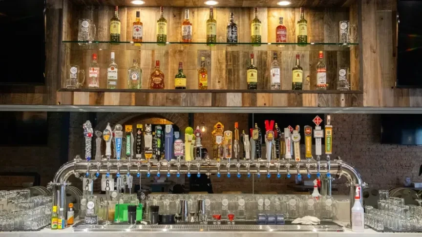 Well-stocked bar with spirits, beer taps, and clean glasses.