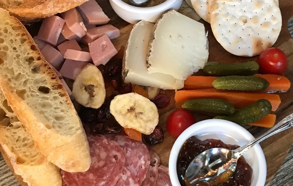 Overhead shot of charcuterie and cheese board with fruit and vegetables.