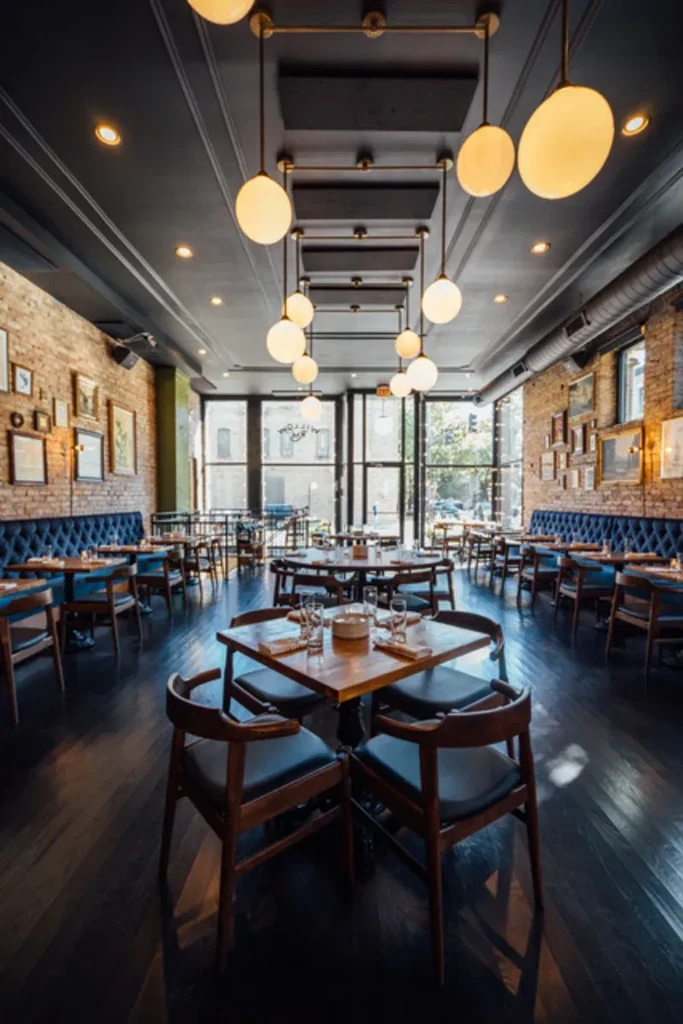 Restaurant interior with blue booths, brick walls, and spherical pendant lights.
