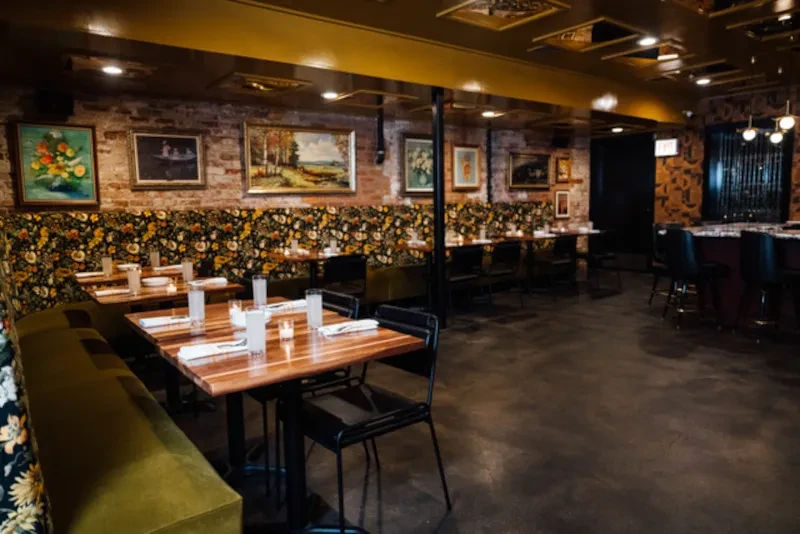 Restaurant interior with tables, a bar, and exposed brick walls.