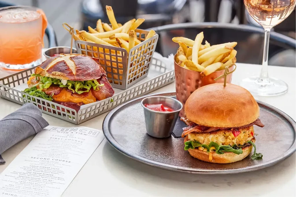 Two gourmet sandwiches, fries, ketchup, rosé, and a cocktail.