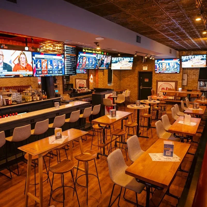 Spacious sports bar interior with a long counter, tables, and TVs.