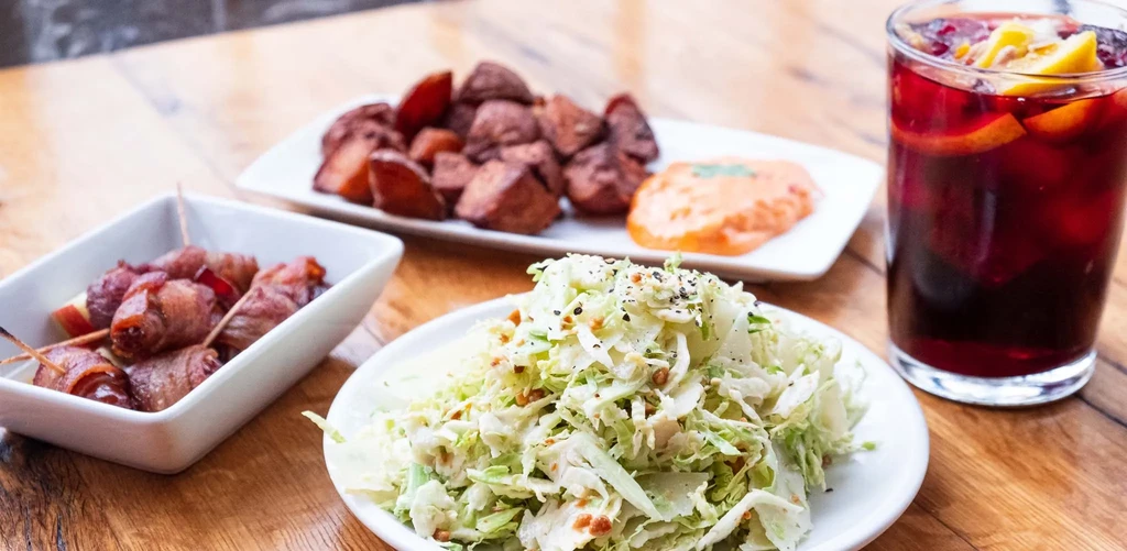 Overhead shot of various dishes and a drink on a wooden table.