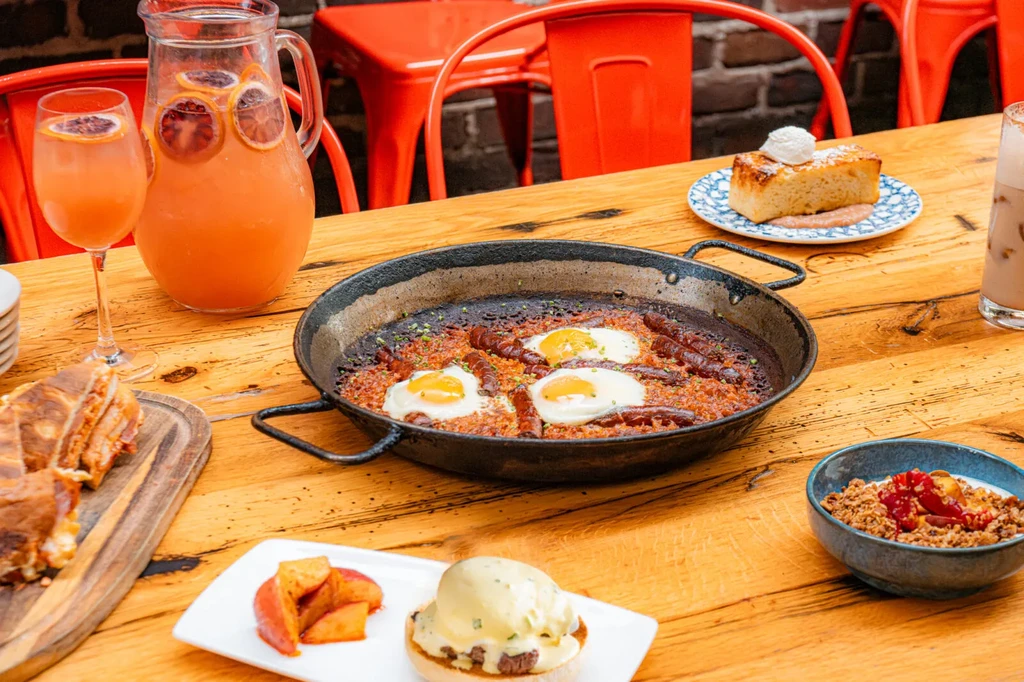 Outdoor restaurant table laden with savory dishes, drinks, and a cake.