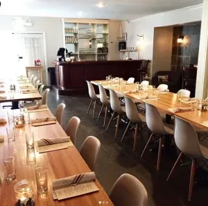 Restaurant interior with long wooden tables set for a meal.