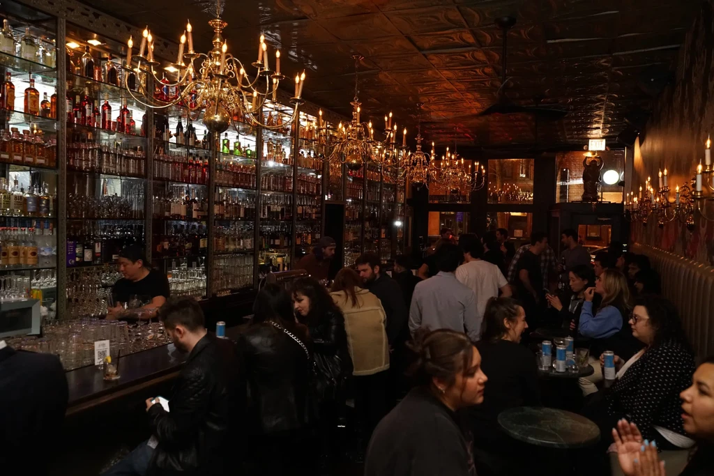 A vibrant, dimly lit bar interior with a large bar and patrons.