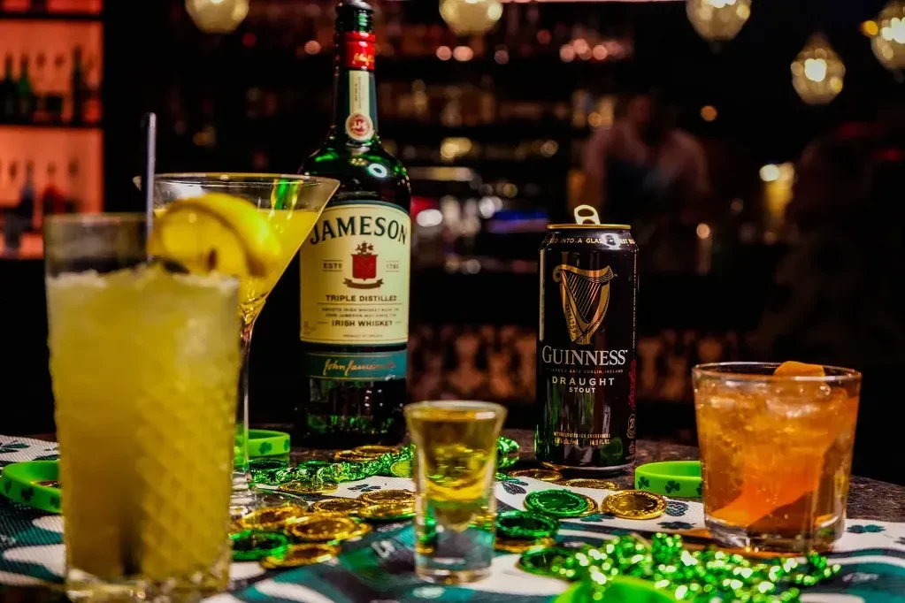 Alcoholic drinks, Jameson, Guinness, and St. Patrick's Day decorations on a table.