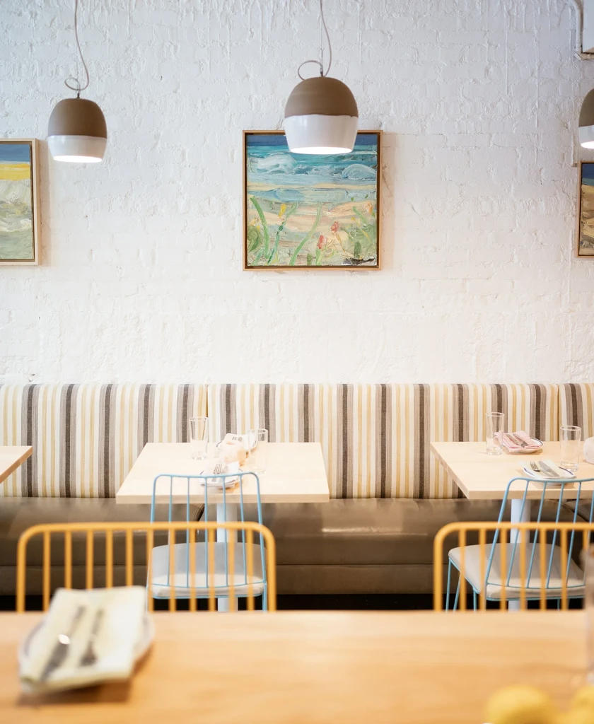 Restaurant dining area with banquette seating, tables, and pendant lights.