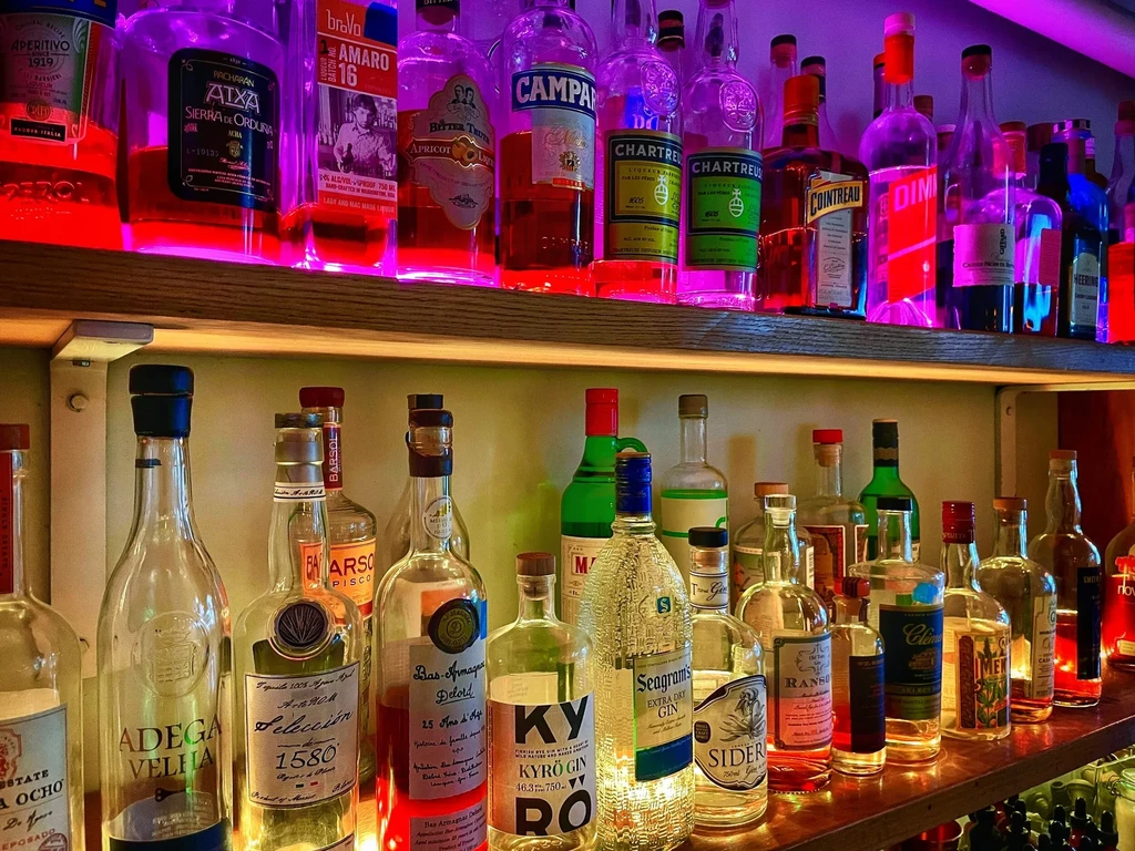 Well-stocked bar with spirits, neon lights, and glowing shelves.