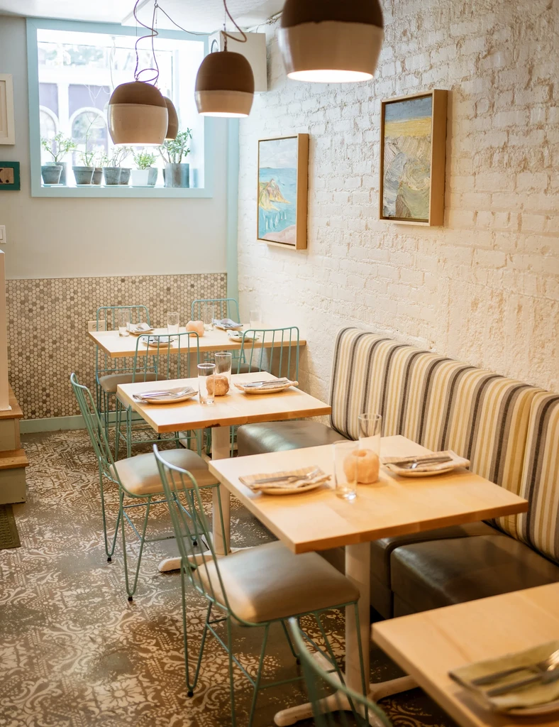 Dining room with wooden tables, teal chairs, and patterned floor.