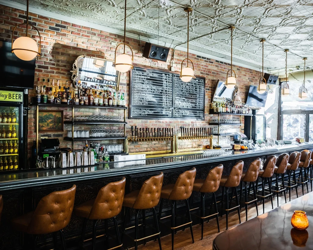 A stylish bar interior with a long counter and many stools.
