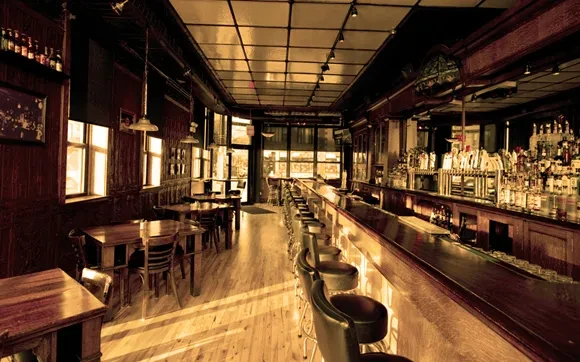 Interior of a rustic bar with a long counter and wooden tables.