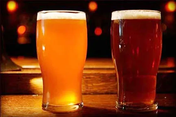 Two pints of beer, one light, one dark, on a bar.